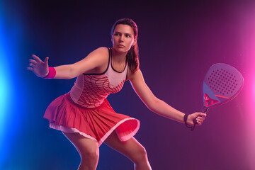 Padel tennis player with racket on tournament. Girl athlete with paddle racket on court with neon colors. Sport concept. Download a high quality photo for design of a sports app or tour events.