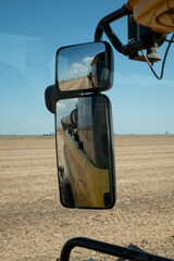 Imagen vertical de espejos en una cosechadora desde donde se ve el campo