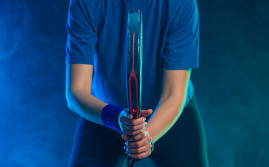 Close-up photo of padel tennis player with racket on tournament. Girl athlete with paddle racket on court with neon colors. Sport concept. No face.