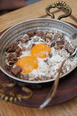 Turkish scrambled eggs with roasted meat in copper pan