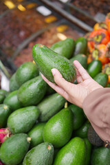 young woman hand holding avocado shopping at retail store 