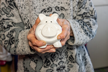 Elderly woman holds a piggy bank in her hands, concept of saving money for retirement