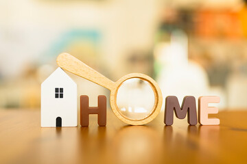 Magnifying glass and looking at HOME text, house selection, real estate concept.