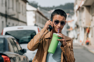 teenager boy on the street with phone and drinking