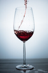 clear crystal glass with red sparkling cocktail served from above, liquid in motion, with the table splashed with liquid
