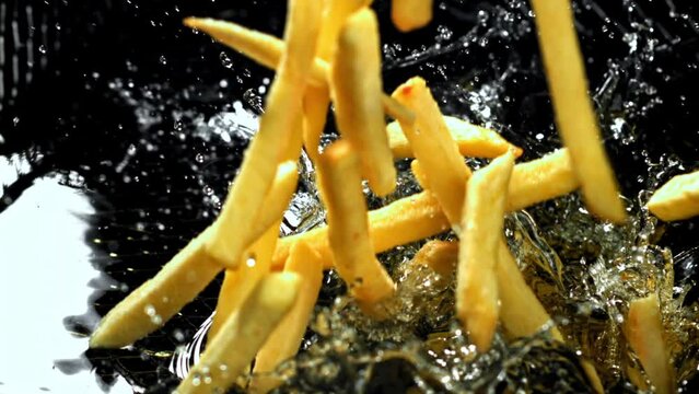 Super slow motion French fries are deep-fried in oil. High quality FullHD footage