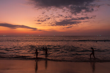 dzieci bawiące się na plaży o zachodzie słońca