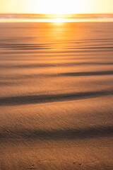 A beach with a sun setting in the background
