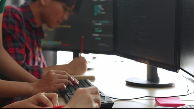 Slow motion back end software developer engineer for computer programming working together on debugging writing computing code, solving complex algorithms display on monitor in office. Burgeoning