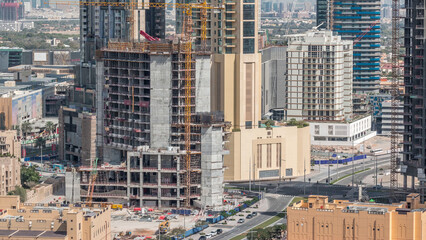 Fototapeta premium Aerial view of a skyscraper under construction with huge cranes in Dubai timelapse. United Arab Emirates