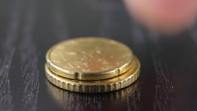 A man puts euro coins one by one in a stack. Close up video.