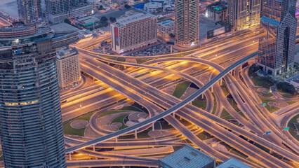 Aerial view of highway interchange in Dubai downtown night to day timelapse.