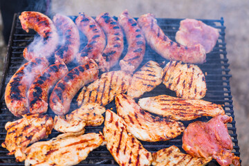 Grilling sausages and pork chops on barbecue grill. BBQ in the garden