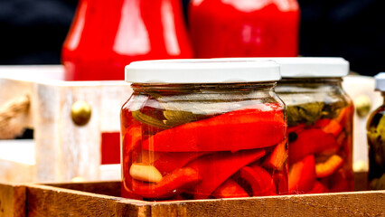 Wooden crate with glass jars with pickled red bell peppers.Preserved food concept, canned vegetables isolated in a rustic composition. - obrazy, fototapety, plakaty