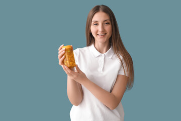 Beautiful woman with bottle of vitamin supplements on blue background