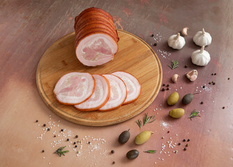 Wooden cutting board with ham on textured vintage background with spices and greens with copy space. Top view.