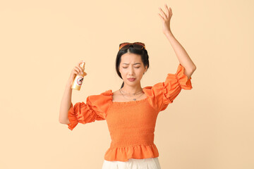 Young Asian woman with mosquito repellent on beige background