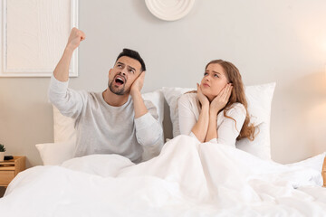 Young couple suffering from loud neighbours in bedroom