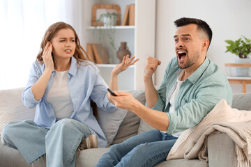 Obraz premium Young couple suffering from loud husband watching TV at home