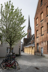historical religious landmark voormalige Kluizekerk church in Lier Belgium. Quiet street scene Koepoortstraat with houses bicycles and tree outdoors on sunny day with no people - 781545183