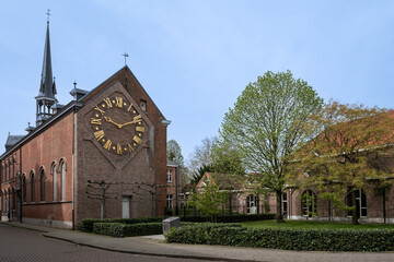 CC Colibrant cultural center in Lier Belgium. Historic clock face retrieved from St. Gummarus Tower displayed on wall of landmark building. Public library space with green trees in pretty city