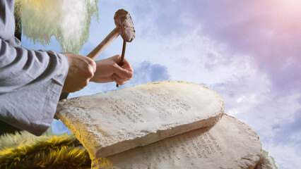 The biblica prophet Moses carves letters from stone on stone tablets of the Ten Commandments