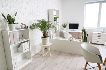Interior of office with table, shelf units and plants