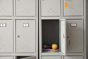 Modern locker with apple, copybooks and pencil case at school, closeup