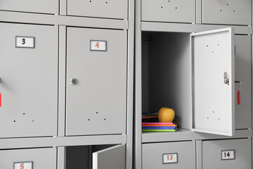 Modern locker with apple, copybooks and pencil case at school, closeup
