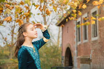 Autumn optimistic portrait. Walls of old architecture in the background with a little girl in a...