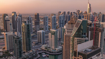 Fototapeta premium Dubai Marina skyscrapers and jumeirah lake towers sunrise view from the top aerial timelapse in the United Arab Emirates.