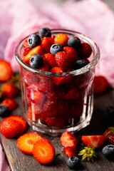Ripe strawberry and blueberries in glass on the rustic background. Selective focus. Shallow depth of field.