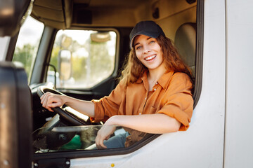 Portrait of young woman professional driver sitting and driving a big truck. Inside of vehicle....