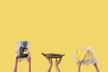 Women with wrapped kitchen supplies on yellow background. Moving concept