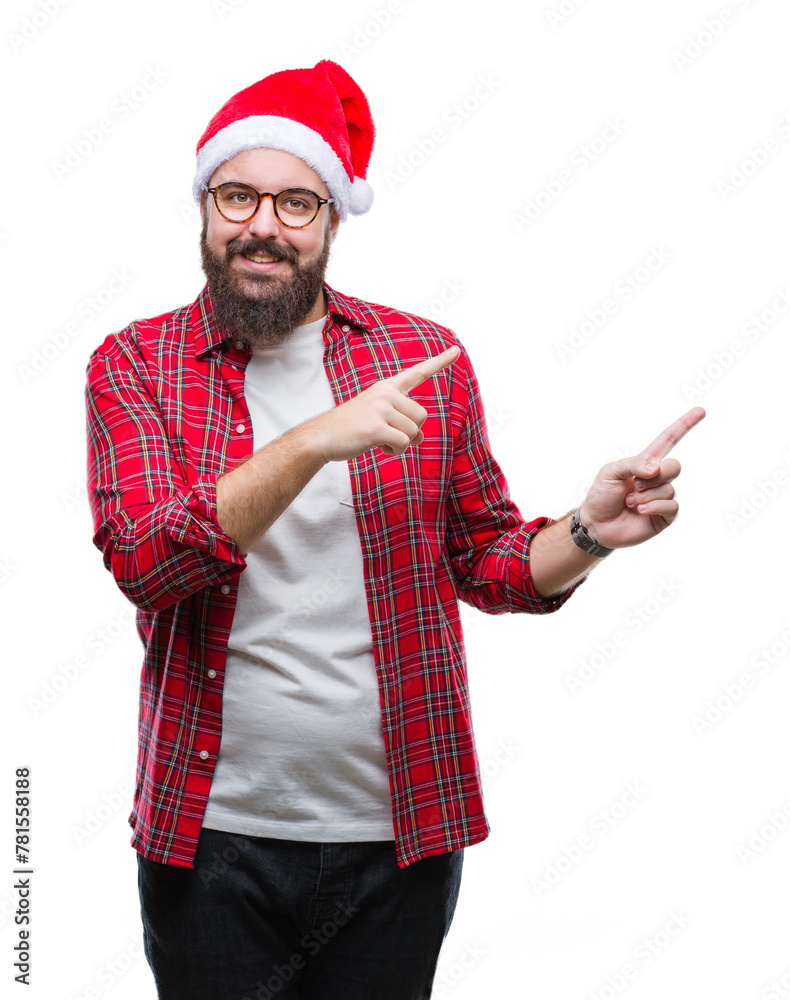 Canvas Prints Young caucasian man wearing christmas hat over isolated background smiling and looking at the camera pointing with two hands and fingers to the side.