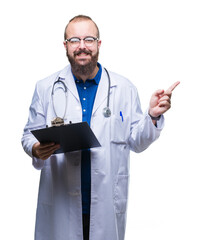 Young doctor man holding clipboard over isolated background pointing and showing with thumb up to the side with happy face smiling
