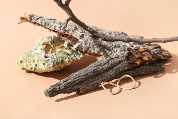 Beautiful earrings with tree bark on beige background, closeup