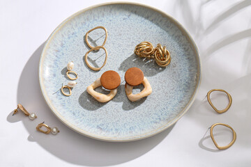 Plate with beautiful earrings on white background