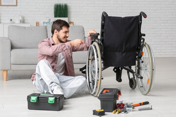 Young man with wrench repairing wheelchair at home