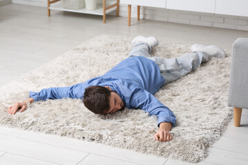 Tired young man lying on carpet at home - obrazy, fototapety, plakaty