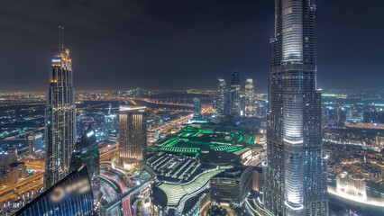 Panoramic skyline view of Dubai downtown with mall, fountains and Burj Khalifa aerial night...