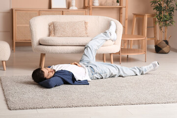 Tired young man sleeping on carpet at home - obrazy, fototapety, plakaty