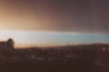 Drops of rain on glass after rain. Rain drops on window glasses surface with cloudy sunset background . Natural Pattern of raindrops isolated on cloudy background. Rainy window.