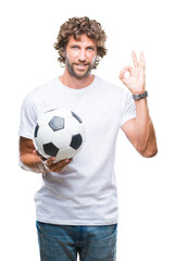 Handsome hispanic man model holding soccer football ball over isolated background doing ok sign with fingers, excellent symbol