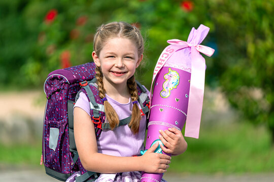 blondes gl&uuml;ckliches sechsj&auml;hriges M&auml;dchen mit Schult&uuml;te und Schulrucksack, erstkl&auml;sslerin, sonniger tag, schulanfang