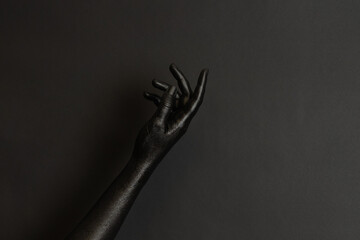 Woman's hands with black paint on her skin on dark background. High Fashion art concept - obrazy, fototapety, plakaty