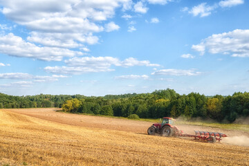 Field work in the summer. A tractor plows the land in an agricultural field