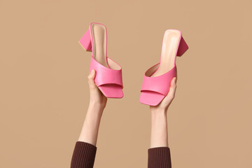Female hands with stylish pink sandals on brown background - obrazy, fototapety, plakaty