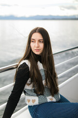 a pensive dreamy young woman sails on a ship on an alpine lake against the backdrop of mountains.beautiful brunette is sad and dreams, enjoying nature.