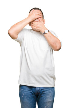 Middle age arab man wearig white t-shirt over isolated background Covering eyes and mouth with hands, surprised and shocked. Hiding emotion